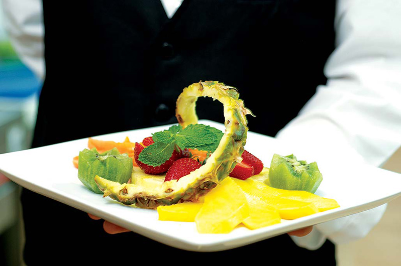 A formal waiter holds a plate with an exotic cold starter