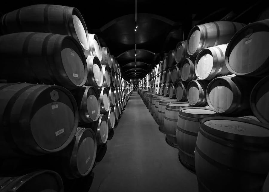 A wine cellar with many barrels stacked on each other in two rows