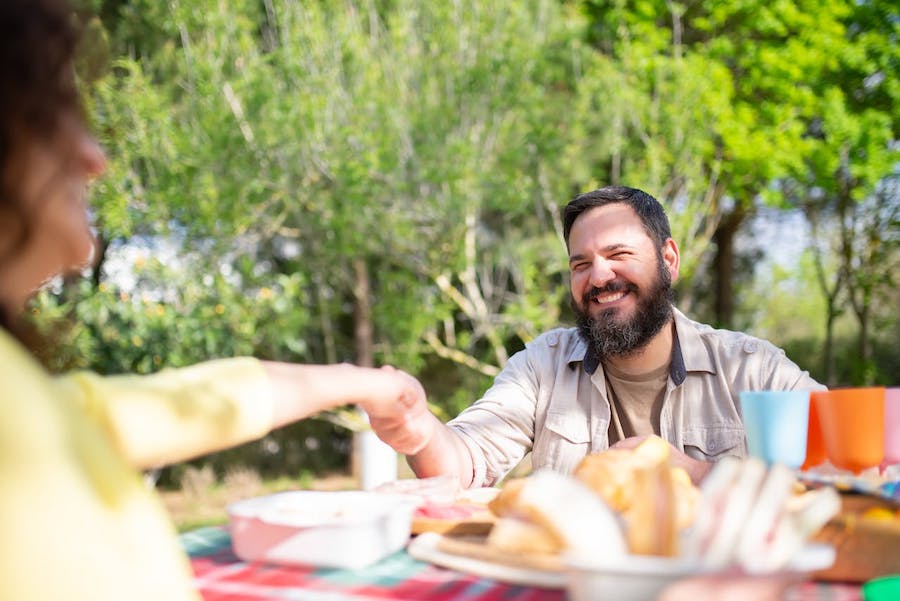 A man hold a woman's hand at lunch outdoors in a winery