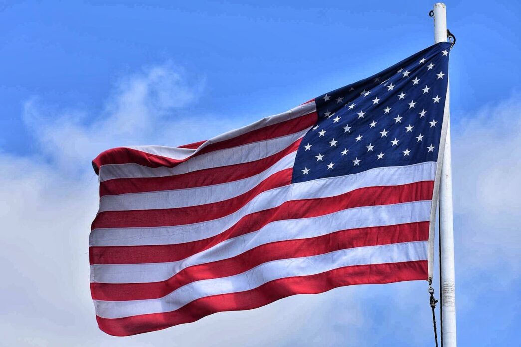 An American flag blowing in the wind against a blue sky