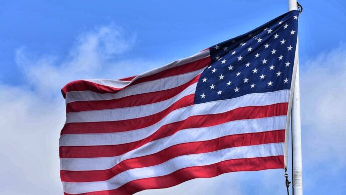 An American flag blowing in the wind against a blue sky