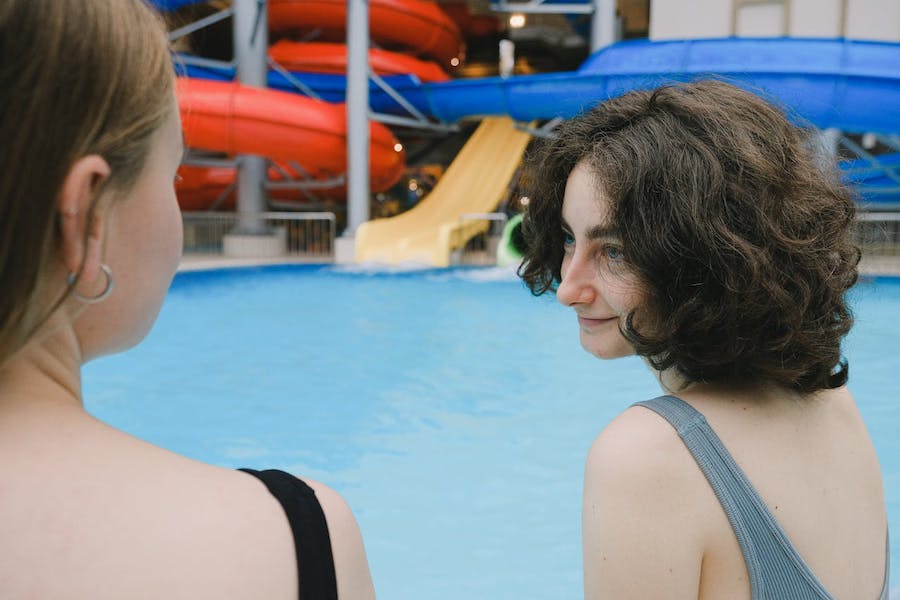 Two women talk wearing swimsuits, while at a waterpark