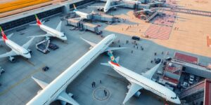 Busy airport scene with planes and passengers bustling.